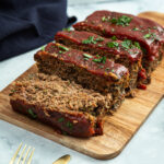 A classic meatloaf on a cutting board, sliced and ready to serve